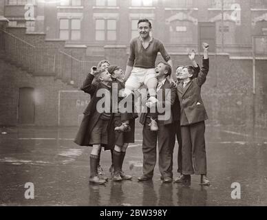 London boy footballeur comme joueur international . Être centre avant en Angleterre équipe contre le pays de Galles . George Butler de l'école de Moreland Road , Coswell Road , a été choisi pour jouer le centre avant pour l'Angleterre dans le match international des écoliers contre le pays de Galles devant être joué à Cardiff samedi . Il jouera probablement pour l'Angleterre contre l'Ecosse dans un autre international de lycéens qui sera joué à Highbury le 12 mai. Photos spectacles , George Butler étant hissé haut par des amis . 18 avril 1934 . 30s, 30s, 1930, 1930, 1930, trente, dix-neuf trente Banque D'Images