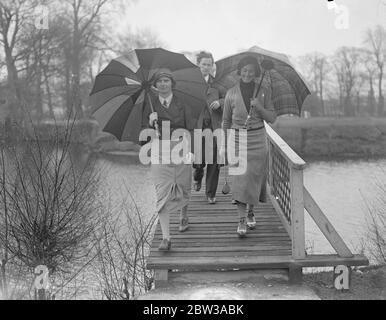 Le tournoi international de golf féminin s'ouvre sous la pluie à Ranelagh . Le tournoi international de l'Union de golf pour dames s'est ouvert sous la pluie au Ranelagh Club , Barnes . Photos Miss Eithne Penpenny ( à gauche ) et Miss B Gaysford , traversant le pont sous les parasols . 11 avril 1934 Banque D'Images