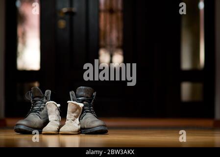 Chaussures d'hiver en cuir pour adultes et enfants debout dans une obscurité couloir Banque D'Images