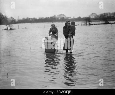 Inondations dans le Berkshire . Deux filles avec un bébé et un enfant marchant dans l'eau d'inondation près de Reading . 30 décembre 1934 Banque D'Images