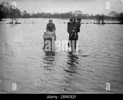 Inondations dans le Berkshire . Deux filles avec un bébé et un enfant marchant dans l'eau d'inondation près de Reading . 30 décembre 1934 Banque D'Images