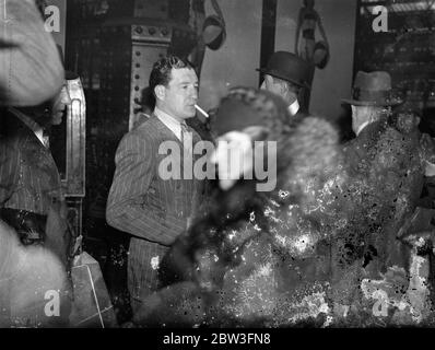 Jock McAvoy , le champion britannique de taille moyenne , qui a été récemment battu sur des points par l'américain John Henry Lewis pour le championnat du monde Light Heavyweigt , est arrivé à Londres à son retour de New York . Il a légèrement blessé la main , mais il va s'entraîner pour son match avec Jack Petersen , le champion britannique de poids lourd . Photos , Jock McAvoy photographié à l'arrivée à Waterloo . 25 mars 1936 Banque D'Images