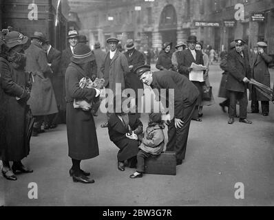 En attente du train de vacances . La grande gare de Londres est maintenant au plus haut de la ruée de Pâques . Des milliers de Londoniens quittent Metropolis pour passer quelques jours dans le pays ou dans les stations balnéaires . Des expositions de photos , deux petits voyageurs à Waterloo discutent du sujet des vacances avec un porteur . 11 avril 1936 Banque D'Images