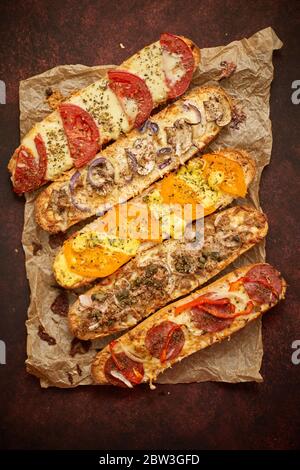 Assortiment de sandwichs cuits au four avec garnitures diverses. Avec fromage fondu, légumes, thon, olives épices Banque D'Images