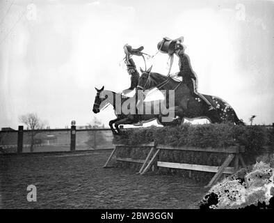 Répétition de cavalerie pour le tournoi Royal . Déselle leurs montages sur des sauts à couper le souffle et de réaliser les plus difficiles exploits avec de superbes chevaux , les troopers de l'école d'équitation à Weedon , Northamptonshire , sont réhéasring pour le tournoi Royal , qui s'ouvre à Olympia le mois prochain . Les hommes qui y participent sont choisis des unités de cavalerie de l'Armée britannique . Photos , selles maintenues en hauteur dans l'air , les troopeurs de l'école d'équitation prennent un saut difficile . 14 avril 1936 Banque D'Images