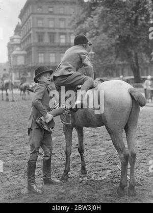 Le plus jeune maître équestre de Hyde Park. Douze ans ! . Michael Rankin , 12 ans, est considéré comme le plus jeune maître d'équitation de Rotten Row , Hyde Park . Il assiste Mme Chapman , femme bien connue instructeur de pilotage . Photos montre , Michael Rapkin aider une jeune fille à monter dans la rangée . 11 juillet 1936 Banque D'Images