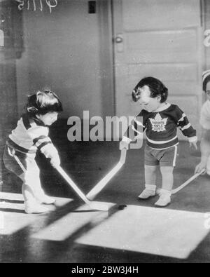 Quins obtient la mauvaise extrémité du bâton ! . Hockey sur glace sur le plancher de la pépinière que les quintuplets de Dionne dernier passe-temps , et tout naturellement , aussi , pour quiconque a entendu parler d'un canadien qui n'était pas intéressé par le hockey sur glace à l'âge avancé de près de deux ans . Bien qu'ils se mélangent parfois entre le bon bout du bâton et le mauvais, les Quins ont vraiment un temps passionnant, mais le brillant du sol joliment poli souffre usuellement ! . Les photos , Yvonne , des Maple Leafs de Toronto , utilise la mauvaise extrémité du bâton pour priver Annette , un Bruin de Boston , du palet dans un match sur t Banque D'Images