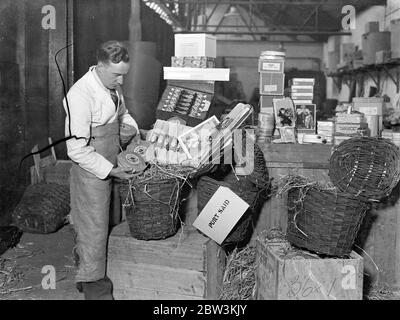 Naffy va tout pour donner aux troupes un joyeux noël . ' Naffy ' , les instituts de la Marine , de l'Armée de terre et de l'Armée de l'Air , travaillent à pleine pression pour s'assurer que les hommes des Services ont un joyeux Noël dans le monde entier . Le tarif de Noël est emballé dans des hampers et les jouets sont emballés dans des caisses aux entrepôts du siège social de Kennington , pour expédition . Photos , jouets d'emballage pour Columbo aux entrepôts du siège . 27 novembre 1935 Banque D'Images