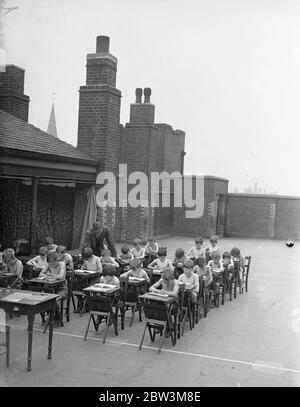 Dans UNE classe par Themselvs pour le progrès! Toit - expérience supérieure à l'école de Londres montre des résultats remarquables . Des résultats étonnants ont suivi l'introduction d'un toit - salle d'école supérieure à l'école de Popham Road Boys , Islington . La salle d'école a été installée l'année dernière pour accueillir 30 garçons en retard et en difficulté . Les dossiers montrent que les élèves ont gagné en taille , en poids et en forme physique générale . La salle de classe est équipée de bureaux pliants , de tableaux noirs , d' une table de maître et d' une machine de pesage . Il a même été équipé par les garçons avec lumière électrique . M. A . W . Dean , le chef de la compagnie , est s. Banque D'Images