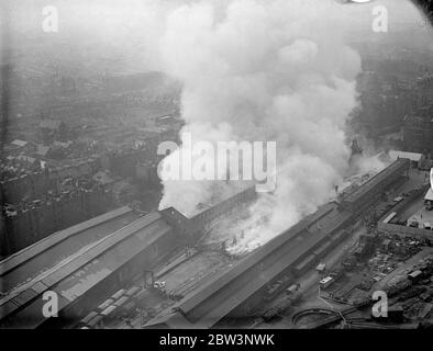 Des centaines de pompiers combattent le grand feu , au dépôt de Brickmavers Arms . Un des plus grands incendies que Londres a vu depuis un certain temps éclate au dépôt d'armes Brickmavers du Southern Railway . Le feu a commencé dans un hangar et s'est propagé à d'autres bâtiments . Des centaines de pompiers ont combattu les flammes tandis que les gens vivant à proximité ont sorti leurs meubles . Photos , une vue aérienne du feu . 4 mai 1936 Banque D'Images