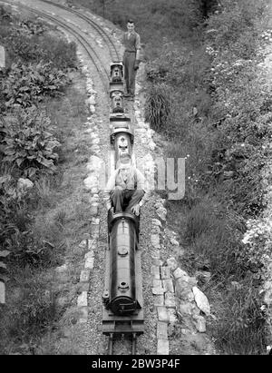 Miniaturisées système ferroviaire construit dans UN jardin de Kenton . Hobby apporte des fonds pour les hôpitaux locaux exprime des spéciaux , et les cargos qui torchent à travers des boutures , des jonctions , des tunnels , sur des ponts et en tirant dans termini à temps - tous les travaux normaux d'un grand chemin de fer - sont accomplis dans l'espace d'un jardin et Kenton , Middlesex . M. J . R . Jeffress de Kenton Grange a construit l'un des chemins de fer miniatures les plus ambitieux dans le domaine de sa maison . Il a conçu sa propre disposition - dehors et construit ses propres locomotives , nommant un George le cinquième . Construit à 0 jauge le système a Banque D'Images