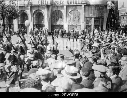 Des troupes d'acier appliquées défilent à travers un attaquant à Liège . Des troupes belges en acier, bien équipées et en train de se faire accompagner à Liège dans une tentative de calme de la ville , ont dû marcher entre les lignes de grévistes qui ont donné le salut communiste et ont crié ' Laissez-les rejoindre ' . Les grévistes et la police ont affronté plusieurs fois dans la ville , au centre de la zone de grève , où plus de 85 000 hommes sont sortis . Les gangs sillent les rues . On craint maintenant que la grève se propage de la province de Liège , dans tout le pays et qu'un million de travailleurs soient impliqués . Photos spectacles , troupes en acier hélifait mar Banque D'Images