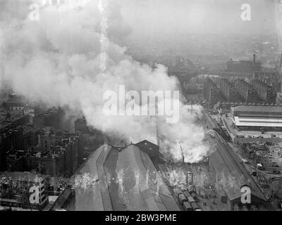 Des centaines de pompiers combattent le grand feu , au dépôt de Brickmavers Arms . Un des plus grands incendies que Londres a vu depuis un certain temps éclate au dépôt d'armes Brickmavers du Southern Railway . Le feu a commencé dans un hangar et s'est propagé à d'autres bâtiments . Des centaines de pompiers ont combattu les flammes tandis que les gens vivant à proximité ont sorti leurs meubles . Photos , une vue aérienne du feu . 4 mai 1936 Banque D'Images