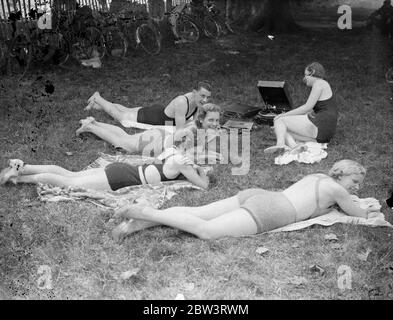 Musique de la rivière Sunny . Bien que les Londoniens aient manqué le soleil , les vacanciers du week-end le long des hauts tronçons de la rivière ont été plus chanceux . Les parties de rivière , la plupart des membres en maillots de bain , se prélasser au soleil ou ont tenu des réunions sportives impromptues au bord de la rivière . Photos : UNE fête de fin de semaine fraîche passe le dimanche après-midi ensoleillé avec des gramophones le long de la rive de la rivière entre Sunbury et Walton . 5 juillet 1936 Banque D'Images