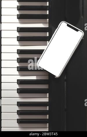 Maquette d'écran de smartphone sur piano électronique à côté des touches noires et blanches. Écran isolé Banque D'Images