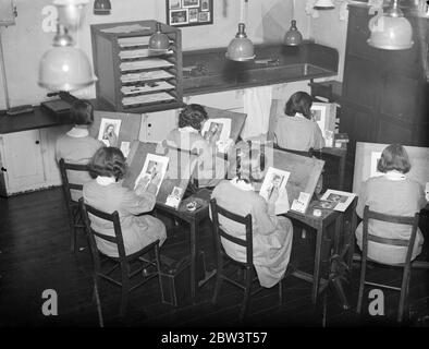 Seulement l'école où les filles sont enseignées à être des photographes . Bloomsbury Trade School for Girls , où les filles sont formées pour devenir des travailleurs qualifiés dans toutes les branches de l'industrie , est la seule école de filles en Angleterre où la photographie est enseignée comme un métier . Les élèves agissent comme modèles pour les autres et sont autorisés à faire des photos pour des cadeaux de noël . Expositions de photos , filles apprenant à retoucher des portraits à la Bloomsbury Trade School for Girls , Londres . 16 décembre 1935 Banque D'Images