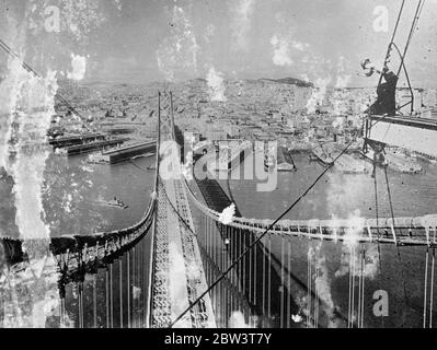 Jeter son ombre sur les eaux . Le pont géant de San Francisco dans les quelques mois suivant l'achèvement Casting son sombre huit et quart de miles ombre sur les eaux de la baie de San Francisco , le gigantesque mais gracieux San Francisco - Oakland Bay Bridge se trouve au-dessus de la ville vers l'achèvement . En novembre, lorsque le pont sera ouvert , les automobilistes auront une nouvelle route vers San Francisco sur la plus grande étendue du monde . Six voies de circulation automobile seront aménagées sur le pont supérieur du pont, tandis que sur le pont inférieur un inter - train de ville et trois trains commerciaux vont fonctionner. Lorsque la mise en place est complète Banque D'Images