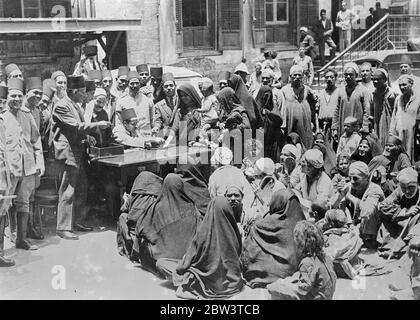 Les almes d'accession du roi Farouk données au Caire les almes pauvres , données par le roi Farouk de 16 ans lors de son accession au trône d'Égypte , ont été distribuées aux pauvres dans les rues du Caire . Les mendiants , aveuglés et boiteux , les mères avec leurs enfants se sont rassemblées devant les tables spéciales où les fonctionnaires blancs - adaptés ont distribué l'argent . Photos : distribuer les almes du roi Farouk aux pauvres dans une rue du Caire . 2 juin 1936 Banque D'Images