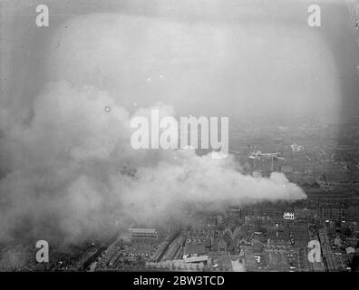 Des centaines de pompiers combattent le grand feu , au dépôt de Brickmavers Arms . Un des plus grands incendies que Londres a vu depuis un certain temps éclate au dépôt d'armes Brickmavers du Southern Railway . Le feu a commencé dans un hangar et s'est propagé à d'autres bâtiments . Des centaines de pompiers ont combattu les flammes tandis que les gens vivant à proximité ont sorti leurs meubles . Photos , une vue aérienne du feu . 4 mai 1936 Banque D'Images