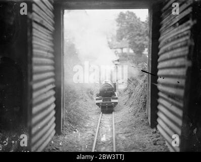 Miniaturisées système ferroviaire construit dans UN jardin de Kenton . Hobby apporte des fonds pour les hôpitaux locaux exprime des spéciaux , et les cargos qui torchent à travers des boutures , des jonctions , des tunnels , sur des ponts et en tirant dans termini à temps - tous les travaux normaux d'un grand chemin de fer - sont accomplis dans l'espace d'un jardin et Kenton , Middlesex . M. J . R . Jeffress de Kenton Grange a construit l'un des chemins de fer miniatures les plus ambitieux dans le domaine de sa maison . Il a conçu sa propre disposition - dehors et construit ses propres locomotives , nommant un George le cinquième . Construit à 0 jauge le système a Banque D'Images