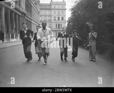 Jesse Owens fait de London Street son circuit . Jesse Owens , le ' Black Panther ' et vainqueur des médailles d'or olympiques de 3 , a présenté une démonstration aux garçons de Londres qui l'ont assiégé pour la corruption de ressources à son hôtel après son arrivée d'Allemagne . Owens doit participer à l'Empire britannique , à l'athlétisme des États-Unis à la ville Blanche ( samedi ) . Photos, Jesse Owens courant avec des garçons à l'extérieur de l'hôtel de Londres. 14 août 1936 Banque D'Images