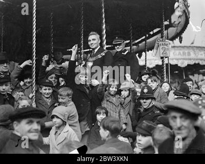 Le maire va rond et rond. Ouvre la foire Peckham's Penny. Après l'ouverture de la foire de Penny à Peckham Rye, le maire de Camberwell (conseiller James Clark) a visité les divers divertissements. La foire est organisée chaque année à l'aide des hôpitaux et des organismes de bienfaisance locaux. Six mille enfants ont reçu gratuitement des loisirs au centre faisant la visite du maire. Expositions de photos : le conseiller James Clark, maire de Camberwell, avec des enfants, sur les ronds-points de la Foire. 31 mars 1937 Banque D'Images