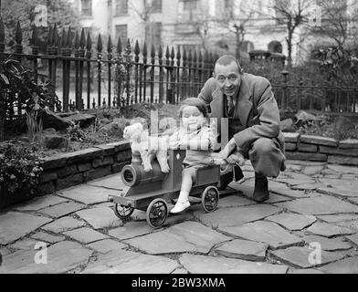 Le Vendredi Saint a été le deuxième anniversaire du vicomte Dupplin, fils de Seigneur et de Lady Kinnoull. Le petit vicomte célèbre l'anniversaire en jouant à des jeux avec son père et deux sœurs plus âgées, Lady Vanetia et Lady June Hay, dans le jardin de leur maison à Regents Park. Photos: Le vicomte Dupplin, âgé de deux ans, va pour un train avec son père, Lord Kinnoull. 26 mars 1937 Banque D'Images