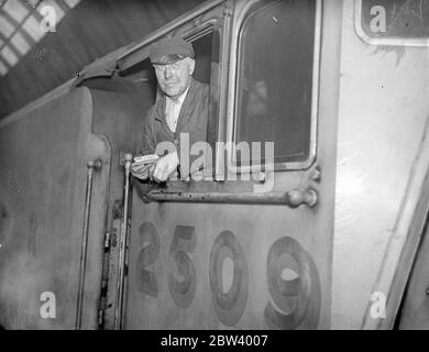 Le pilote de record express Silver Jubilee fait sa dernière course. Le chauffeur George Haygreen, le chauffeur du Silver Jubilee Express, a établi le record de 113 miles par heure, la vitesse de chemin de fer britannique la plus rapide, le mois dernier, a fait sa dernière course et a pris sa retraite lorsqu'il est arrivé à la gare de King's Cross sur le Silver Link Express aujourd'hui, vendredi. Le chauffeur Haygreen prend sa retraite après 37 ans de service ferroviaire. Photos : le chauffeur Haygreen dans la cabine du Silver Link Express à King's Cross à la fin de sa dernière course. 18 septembre 1936 Banque D'Images