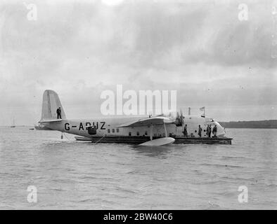 Les bateaux-mouches utilisent un nouveau radeau d'embarquement pour la première fois. Cygnus débarque 19 passagers. Deux bateaux volants ont utilisé le nouveau radeau d'embarquement - conçu pour éviter d'endommager leurs coques métalliques - pour la première fois à Southampton. Cygnus débarque 19 passagers et l'envoi de courrier et d'or. La chasse reliée à l'extérieur a également utilisé le radeau. Expositions de photos Cygnus, amarré au radeau pour débarquer 19 passagers et décharger le courrier et la construction 10 avril 1937 Banque D'Images