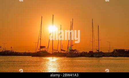 Silhouettes de yachts avec de hauts mâts au coucher du soleil dans le port Banque D'Images