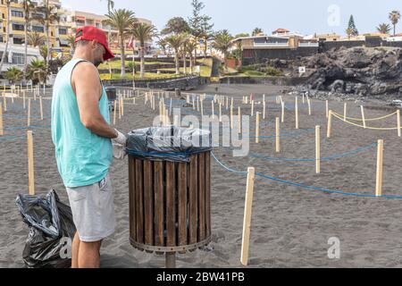 L'employé déverse des poubelles sur la plage avec des zones en périmètre pour maintenir une distance sociale, à deux mètres de distance et un accès contrôlé au public Banque D'Images