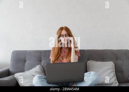 Femme parlant au téléphone tout en travaillant sur un ordinateur à la maison. Résolution des problèmes Banque D'Images