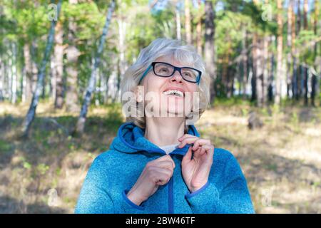 Rire de la femme d'âge moyen avec des lunettes marchant dans le parc. Jour d'été ensoleillé. Le concept de liberté et de joie. Banque D'Images