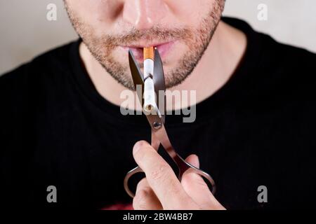 la moitié inférieure du visage d'un homme non rasé avec une cigarette et des ciseaux, en gros plan Banque D'Images