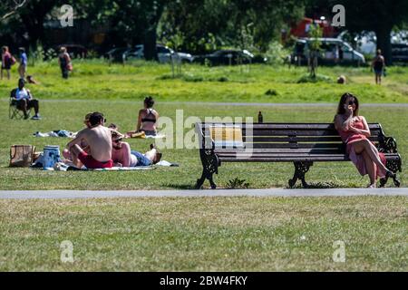 Londres, Royaume-Uni. 29 mai 2020. Les gens apprécient le soleil sur Clapham Common après que le gouvernement a assoupli les restrictions et permis aux gens de se rencontrer - le Conseil de Lambeth a remplacé les panneaux pour dire rester alerte et pour permettre aux gens de s'asseoir sur les bancs. Le « verrouillage » facilité se poursuit pour l'épidémie de coronavirus (Covid 19) à Londres. Crédit : Guy Bell/Alay Live News Banque D'Images