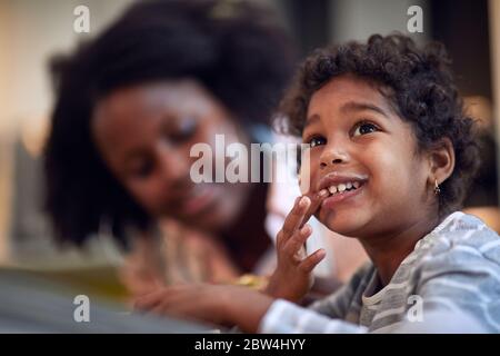 Bonne fille avec moustache au lait au petit déjeuner chez sa mère. Banque D'Images