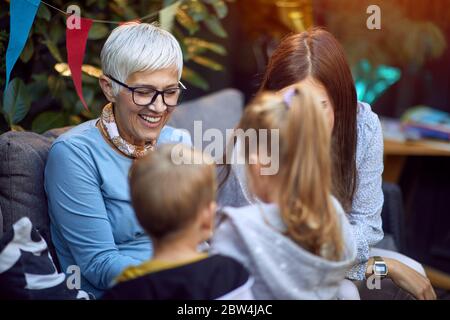 Femme aîée souriante s'amuse avec ses petits-enfants à l'extérieur à la maison. Banque D'Images