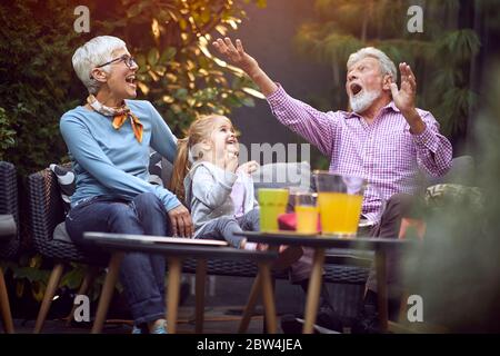 Petite-fille gaie passant du bon temps et amusant avec leurs grands-parents heureux. Banque D'Images