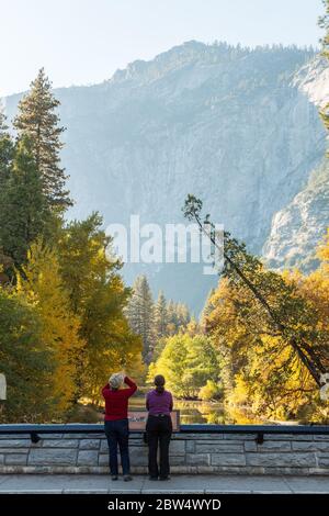 Deux touristes observent et photographient le paysage depuis le pont Sentinel dans le parc national de Yosemite, Californie, États-Unis Banque D'Images