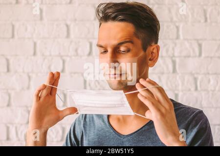 Portrait d'un hipster confus avec un drôle de coup de soleil peau bronzée portant un masque médical. Jeune homme en colère avec des lignes de bronzage sur le visage de fac protecteur Banque D'Images