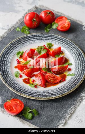 Salade de printemps de tomates fraîches, de coriandre et de grenade. Banque D'Images