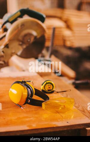 Vêtements de travail professionnels pour les travailleurs de scierie. Lunettes de protection et écouteurs sur la table principale de menuiserie à l'usine de production de bois. J Banque D'Images