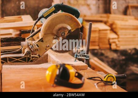 Poste de travail professionnel avec scie circulaire électrique, lunettes de protection et écouteurs. Équipement de protection pour charpentier à la production de bois Banque D'Images