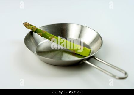 photo de concept, asperge énorme sur un petit plateau en acier sur fond blanc. Banque D'Images