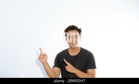 homme asiatique attrayant montrant des annonces sur fond blanc avec son pouce Banque D'Images