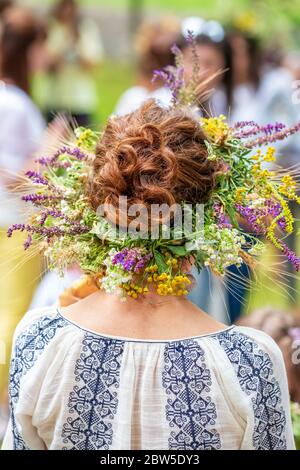 Femmes non identifiées dans des robes traditionnelles avec des couronnes de solstice d'été faites à partir de fleurs de champ, de graminées et de céréales. Banque D'Images