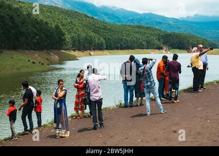 Les touristes indiens posent pour des photos au bord du lac à Echo point, sur le réservoir du barrage de Mattupatti à Munnar, Kerala, Inde Banque D'Images