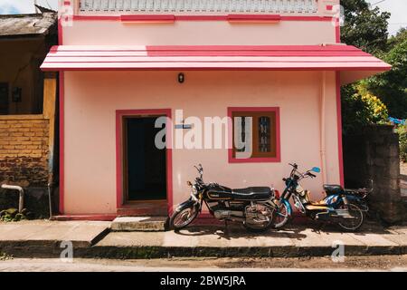 Une petite maison rose vif à Kumily, en Inde, avec deux motos garées devant Banque D'Images