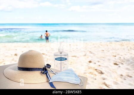 Vacances dans la nouvelle normalité après la pandémie du coronavirus COVID-19. Concept de tourisme montrant chaise longue sur plage de sable avec chapeau de plage, désinfectant pour les mains, Banque D'Images