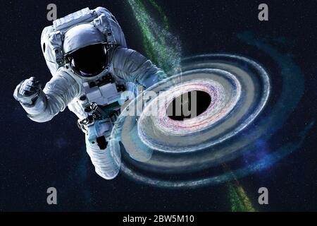 Astronaute près du trou noir coloré quelque part dans l'espace. Un arrière-plan spectaculaire. Science-fiction. Des éléments de cette image ont été fournis par la NASA Banque D'Images